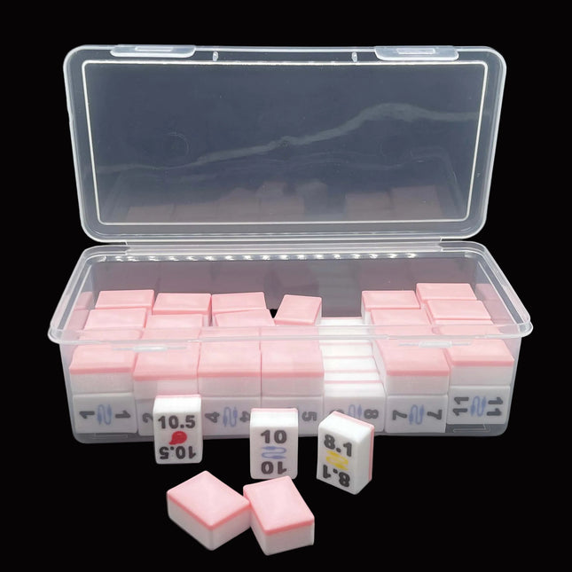 A clear plastic storage case containing multiple small white and pink rectangular tiles - Mahjong style- with a few matching tiles placed in front on a dark background.