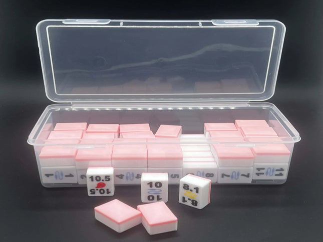 A clear plastic storage case containing multiple small pink-and-white rectangular blocks, with three of the blocks placed in front on a dark background.
